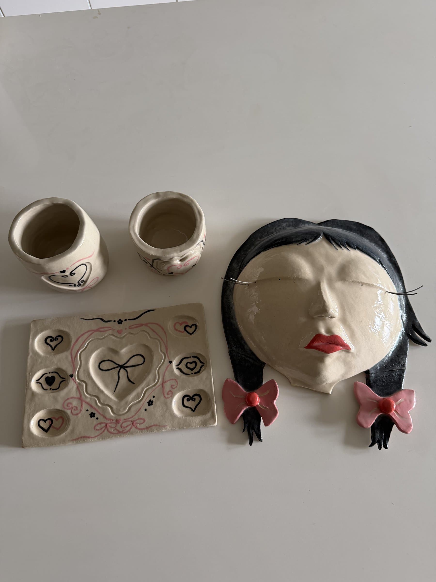 The finished set: glazed brush cups, heart palette tray, and the ceramic girl with black hair, red lips, and pink bows