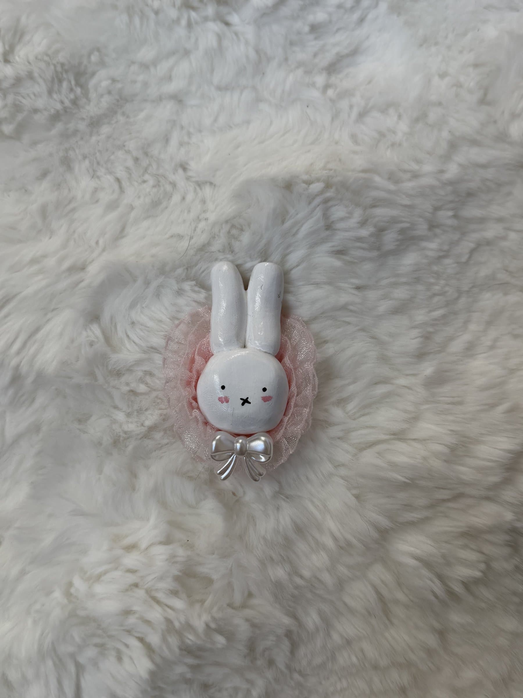 White clay bunny with pink cheeks in a shimmery pink lace ruffle with a pearl bow